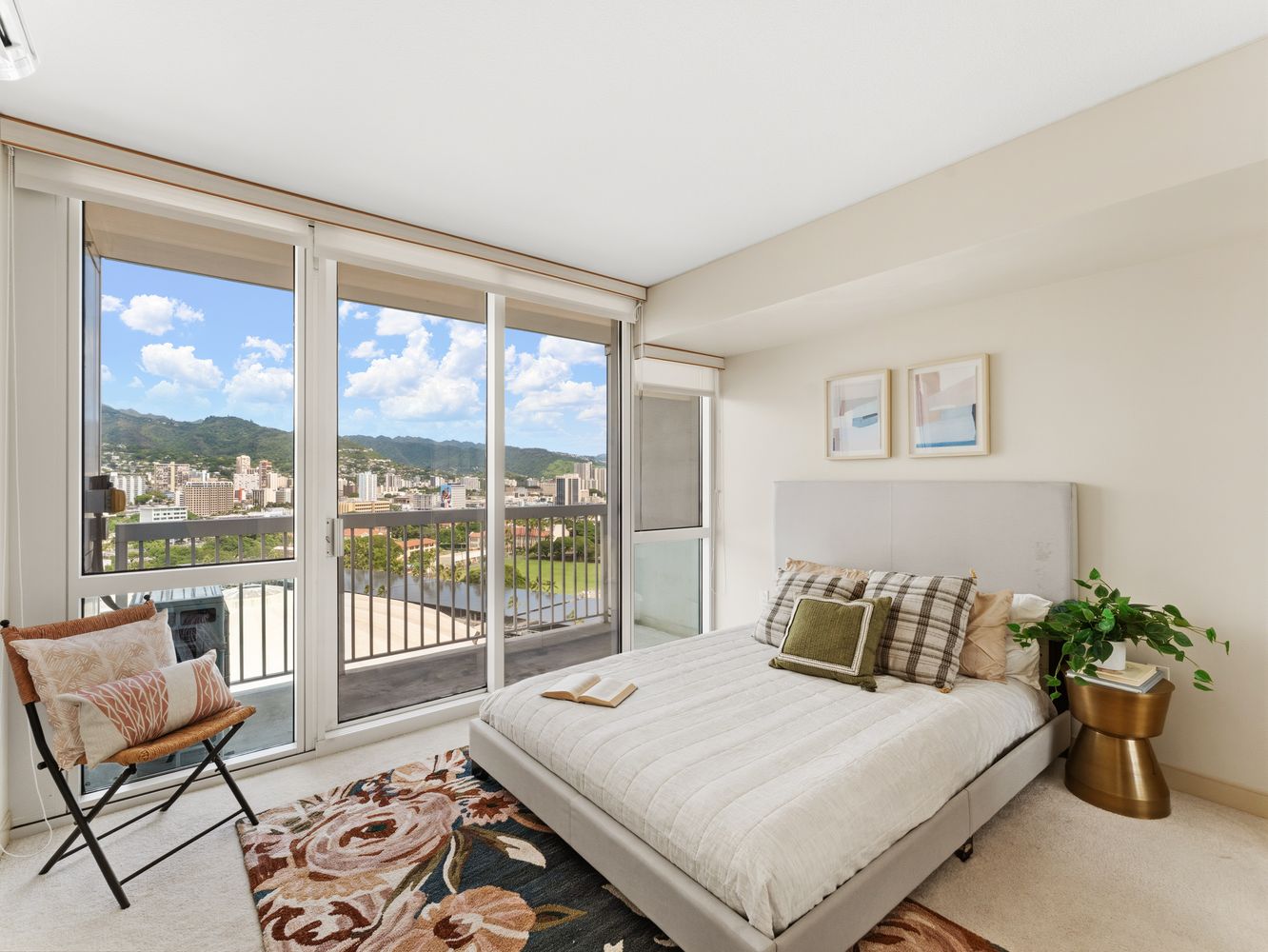 Bedroom with bed, accent chair and sliding balcony doors overlooking the waterway and city
